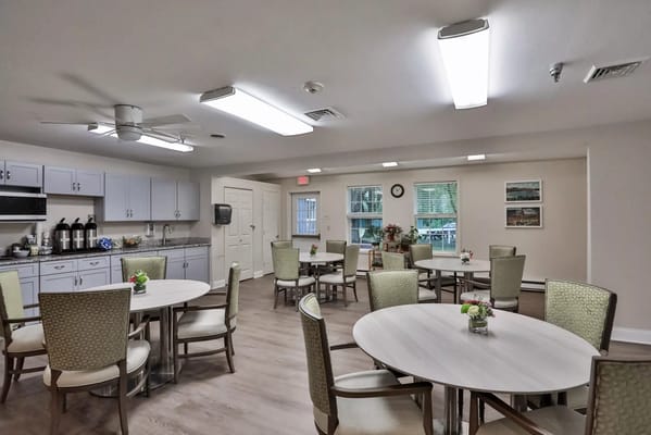 Bright and inviting common area with tables and chairs at Peregrine Senior Living.