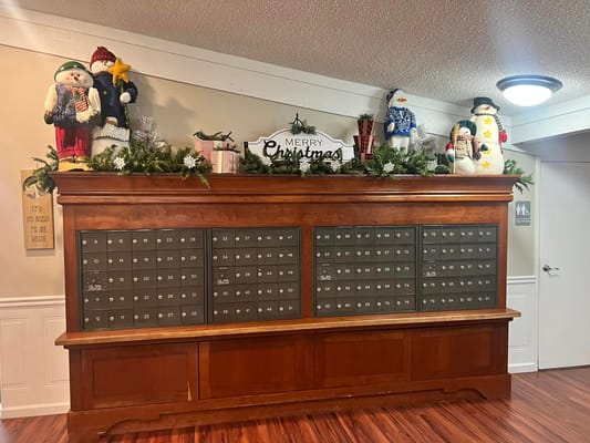 Wooden mailboxes decorated with Christmas snowmen and greenery.