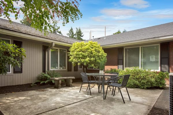 Patio area with a table and chairs surrounded by greenery