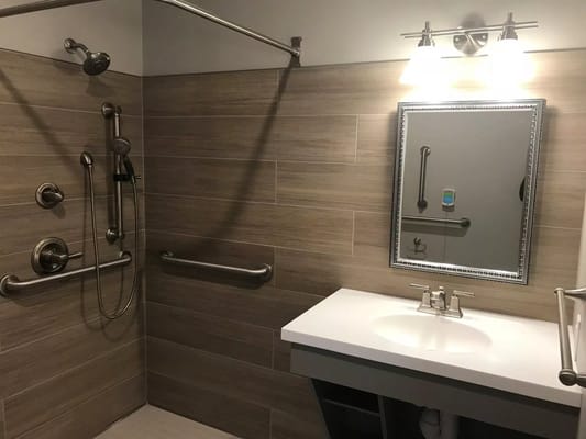 Spacious bathroom with grab bars and shower fixtures
