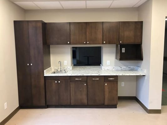 Kitchenette with wooden cabinets and marble countertop