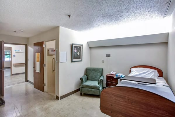A private resident room with a bed and chair