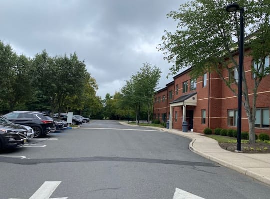 Parking area with trees and nearby residential building.