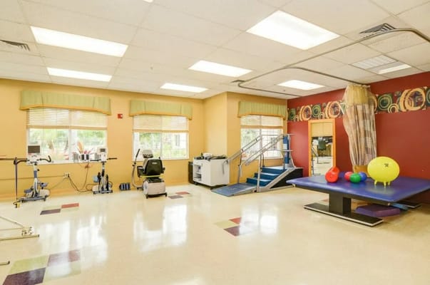 Bright therapy room with exercise equipment and therapy mats