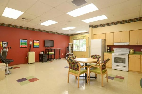 Bright activity room with a round table and kitchen amenities
