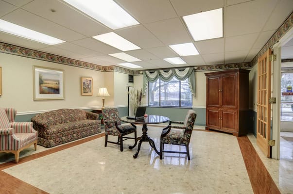 Cozy lounge area with floral sofas and a round table.