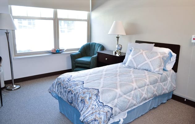 Brightly decorated private resident room with a bed and chair