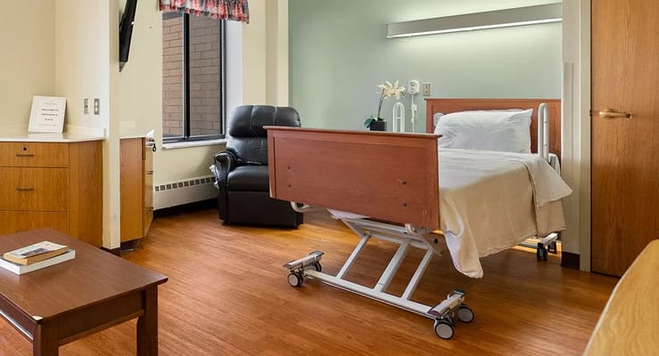 A private bedroom featuring a hospital bed and a comfortable chair.