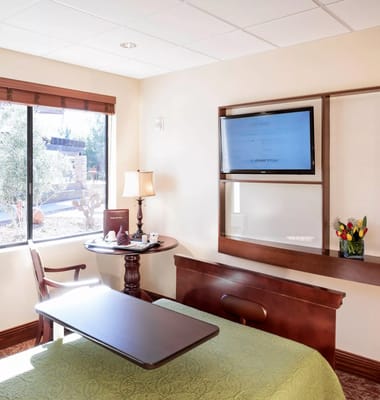 Cozy room with bed, lamp, and TV in Pueblo Norte Senior Living Community