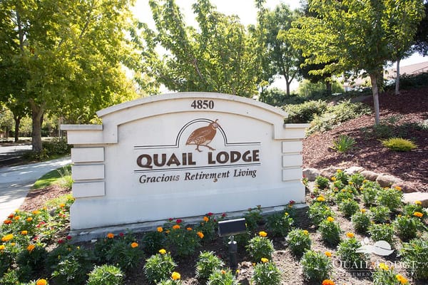 Sign for Quail Lodge Retirement Community surrounded by flowers