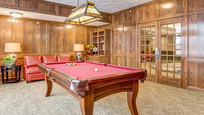 Pool table in an inviting game room with wooden walls