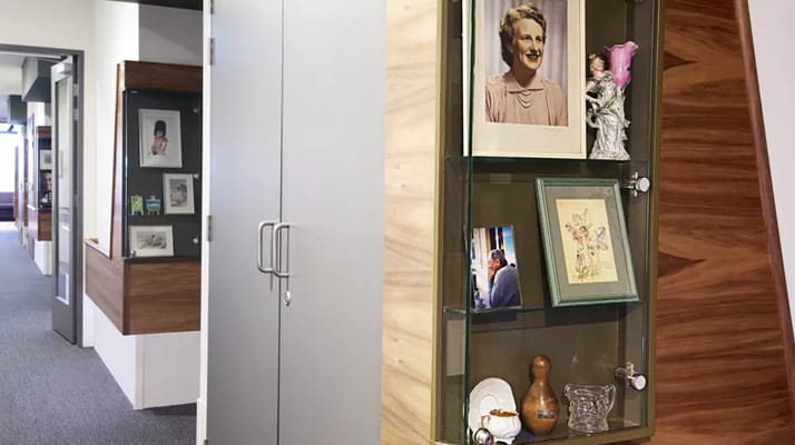 A hallway with a display cabinet featuring photographs and decorative items.