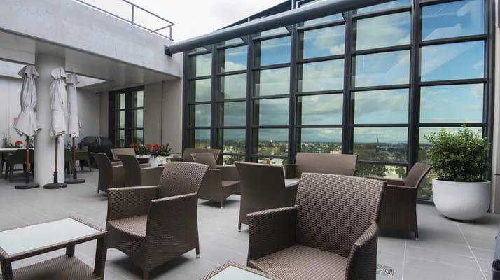 Stylish rooftop lounge with wicker chairs and large glass windows