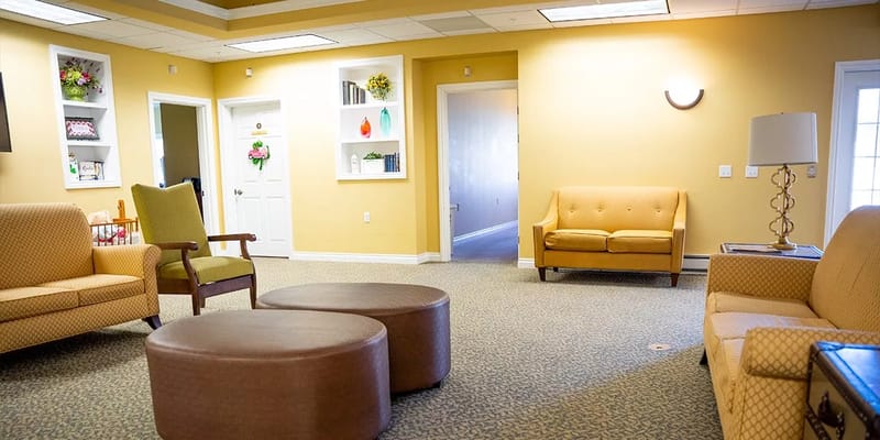 Cozy living room with seating and shelves at Reflections Memory Care
