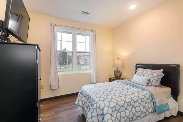 Bright and cozy bedroom with a bed, bedside table, and window