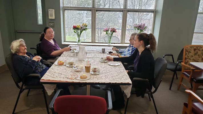 Four residents sitting around a table enjoying tea and snacks.