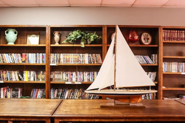 Model sailboat displayed on a wooden table in the library