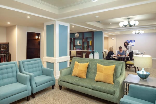 Common area with seating and staff interacting with residents