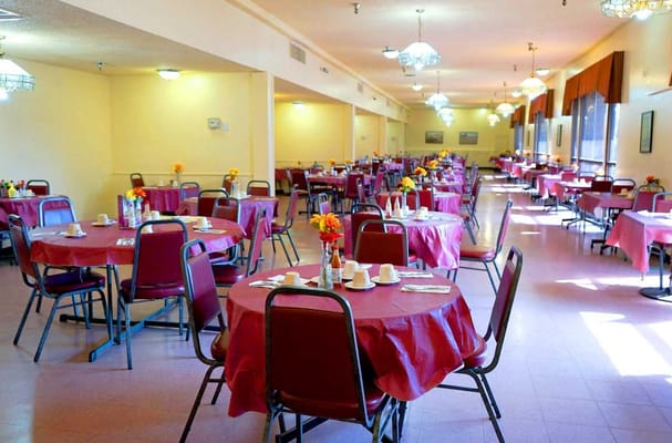 Spacious dining room with red table covers and flowers