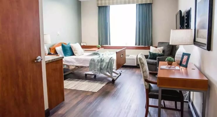 Well-furnished private room with a bed, chair, and desk.