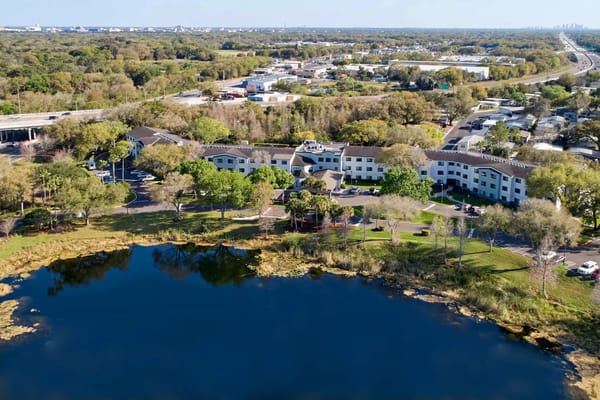 Aerial view of Renaissance North Tampa senior living facility near a lake.