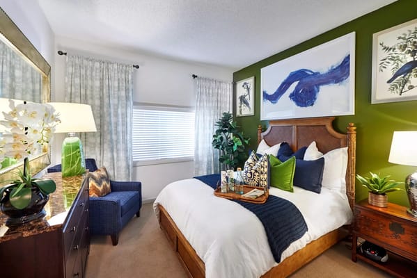 Well-decorated bedroom with green accent wall and decorative pillows