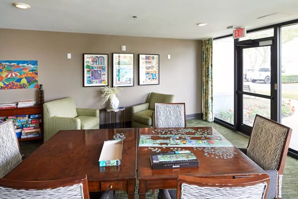 A cozy common area with puzzle pieces on a table and artwork on the walls.