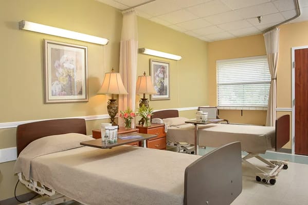 Two beds in a resident room with lamps and floral decor