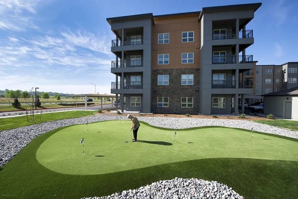 A resident putting on a golf green outside Revel Province senior living facility.