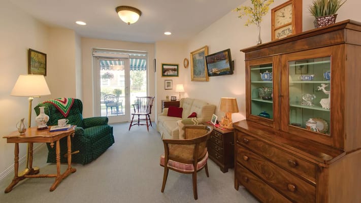 A comfortable living room with a green armchair, wooden furniture, and natural light.