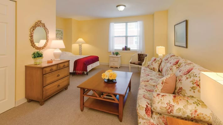 A cozy room with a bed, sofa, and dresser at the nursing facility
