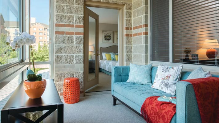 A cozy balcony with a view, featuring a blue sofa and potted plants.