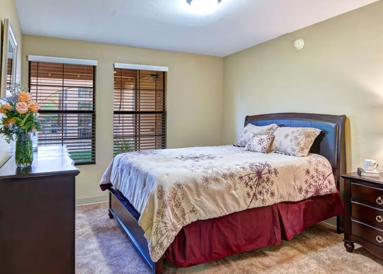 A well-furnished bedroom with a bed, nightstand, and floral decorations.