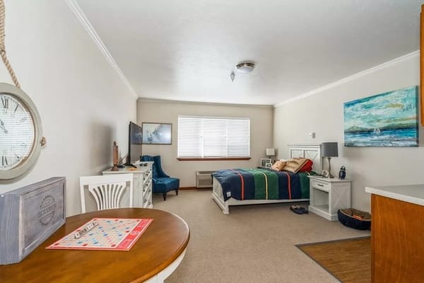 A cozy bedroom featuring a bed, a chair, and a small dining table.