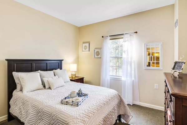 A well-furnished bedroom with sunlight streaming through a window.
