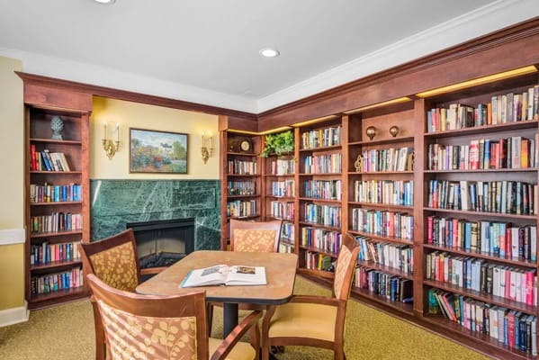 A cozy library with bookshelves and a table in River Ridge at Avon