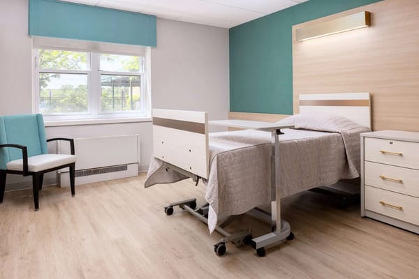 Brightly lit resident room with bed and chair