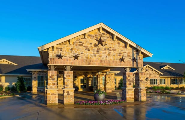 Entrance of Riverside Oxford Memory Care facility with stone façade and landscaping.