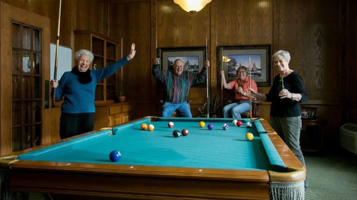 Four seniors playing billiards in a cozy lounge area