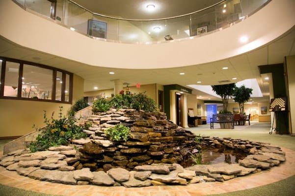 A beautifully landscaped indoor waterfall surrounded by plants and rocks.