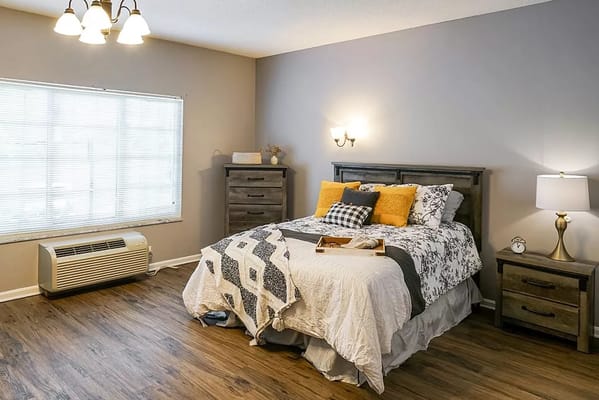 A well-decorated bedroom with a window, bed, and dresser.
