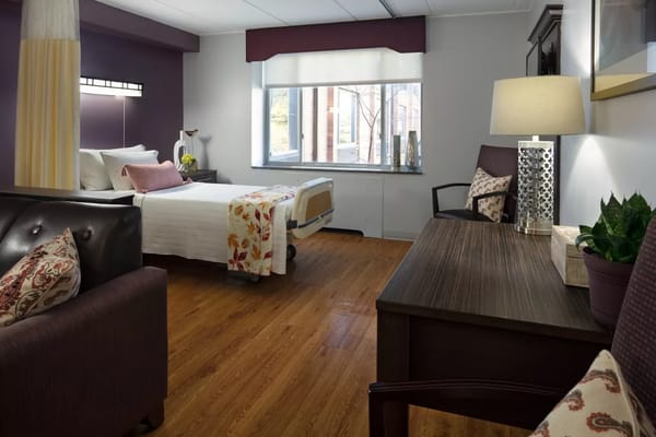 A well-furnished resident room with a bed and desk