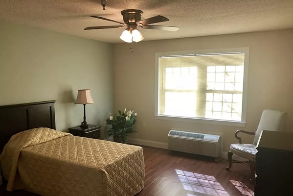 A private resident room with a bed and chair
