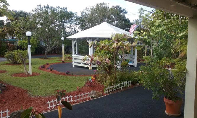 A gazebo surrounded by flowering plants and manicured lawns.