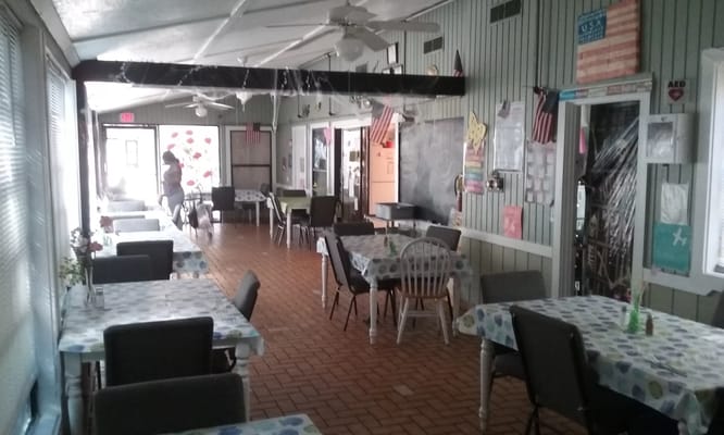 Dining area with tables and chairs in Rustic Retreat senior living facility
