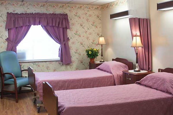 Private resident room with two beds and floral wallpaper