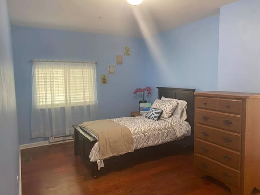 A cozy private room with a bed and dresser