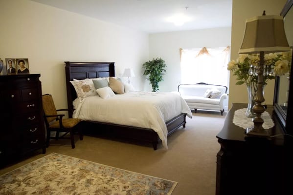Spacious bedroom with a bed, seating area, and dresser.