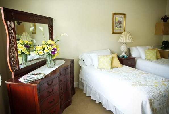 Cozy shared bedroom featuring two beds, a dresser, and flowers in a vase