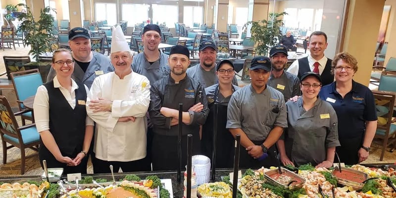 Kitchen staff posing beside a buffet at Sable Lodge Retirement Community